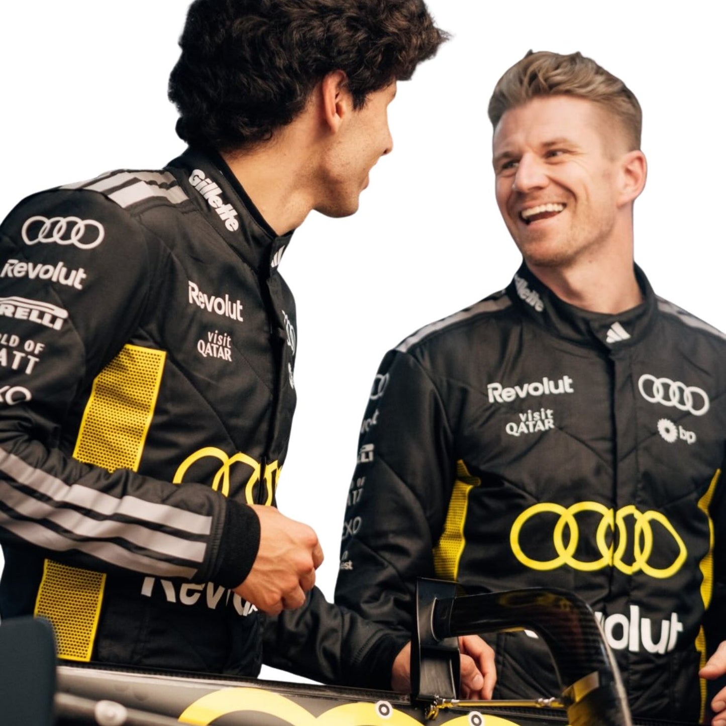 Two men in Audi racing suits shaking hands with a car in the foreground.