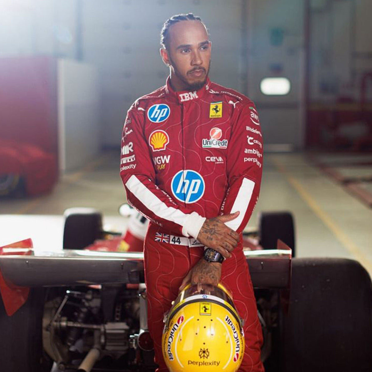 Lewis Hamilton 2025 F1 Race Replica Costume Ferrari Monza GP with various sponsor logos standing next to a Formula 1 car.