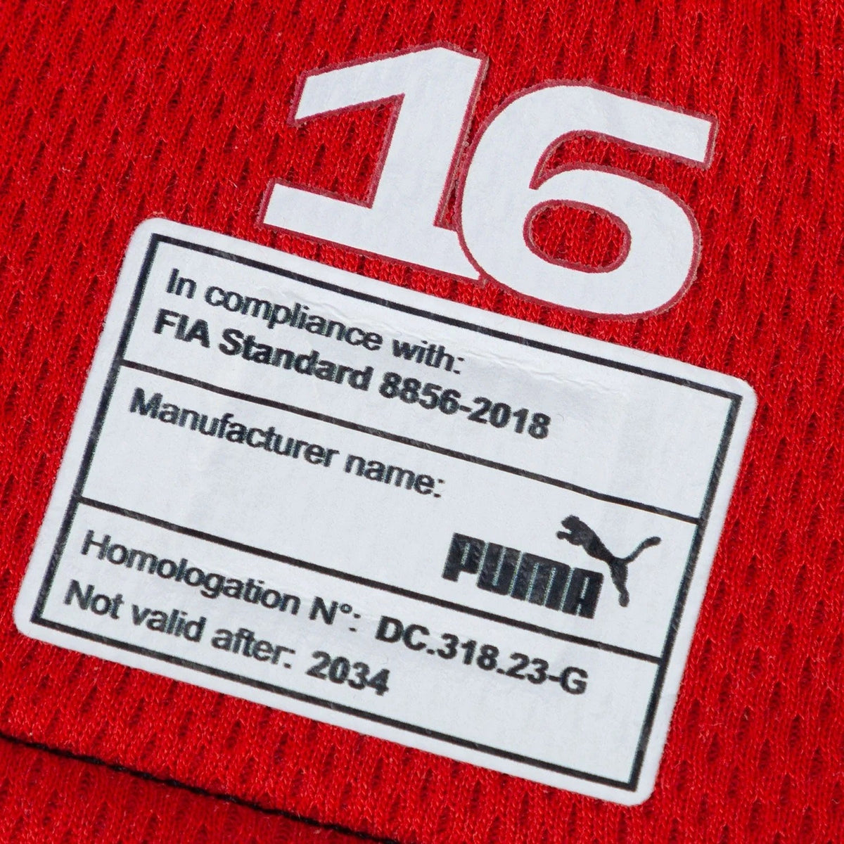 Close-up of a red Charles Leclerc 2024 Race Gloves Replica F1 Ferrari with a white label displaying Puma branding and text.