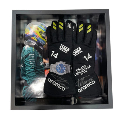Pair of black Fernando Alonso 2024 Race Gloves F1 Aston Martin with branding in a display case, featuring a helmet and watch.