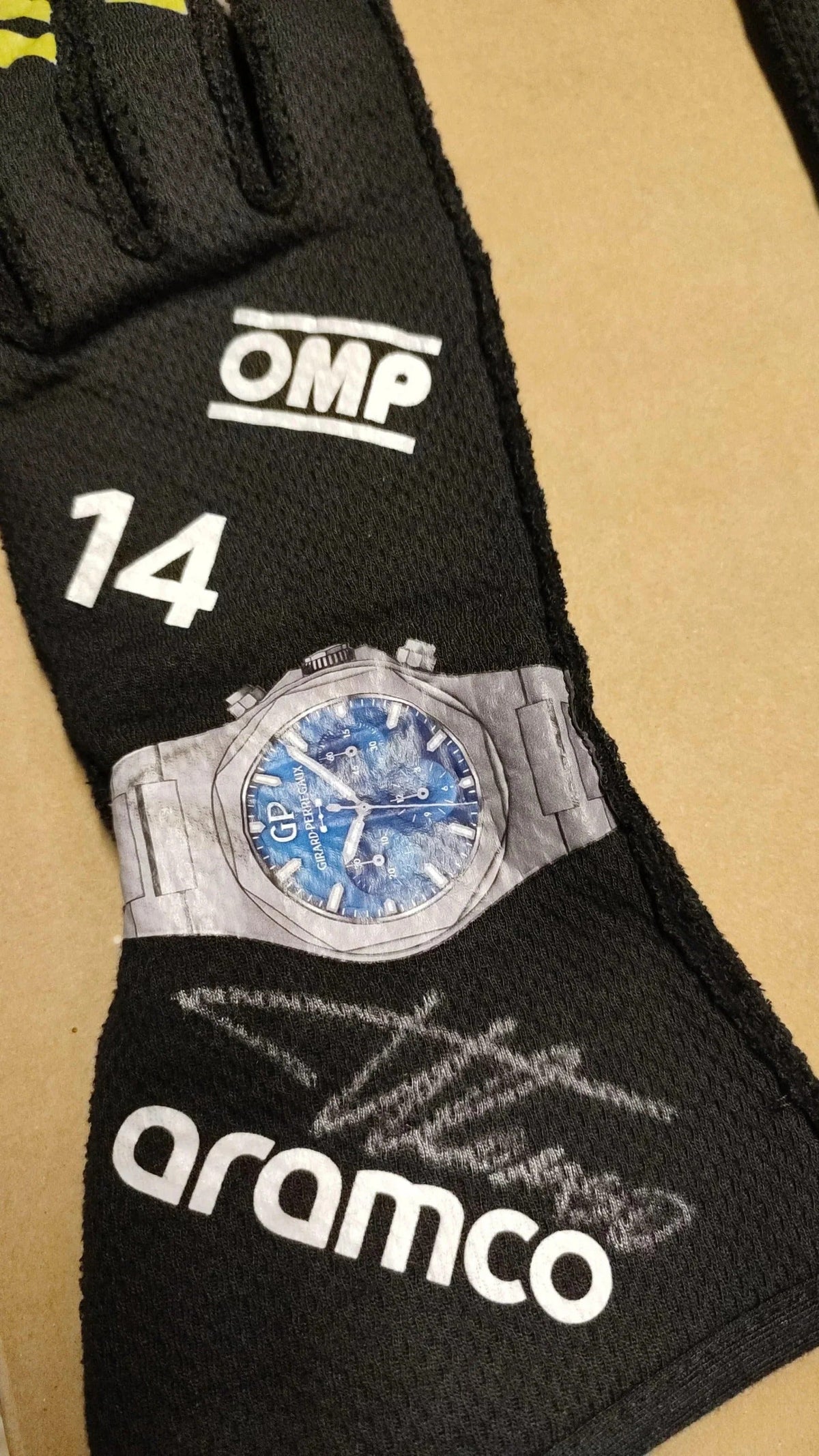 Black Fernando Alonso 2024 Race Gloves F1 Aston Martin with 'OMP' and 'aramco' branding, featuring a silver watch with blue face.