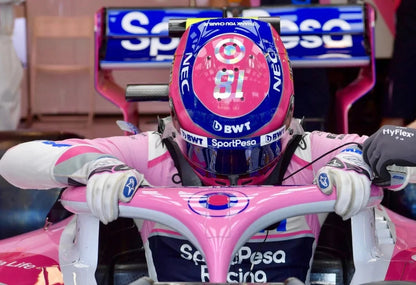 Lance Stroll in a racing suit and helmet inside a pink and blue Formula 1 car.