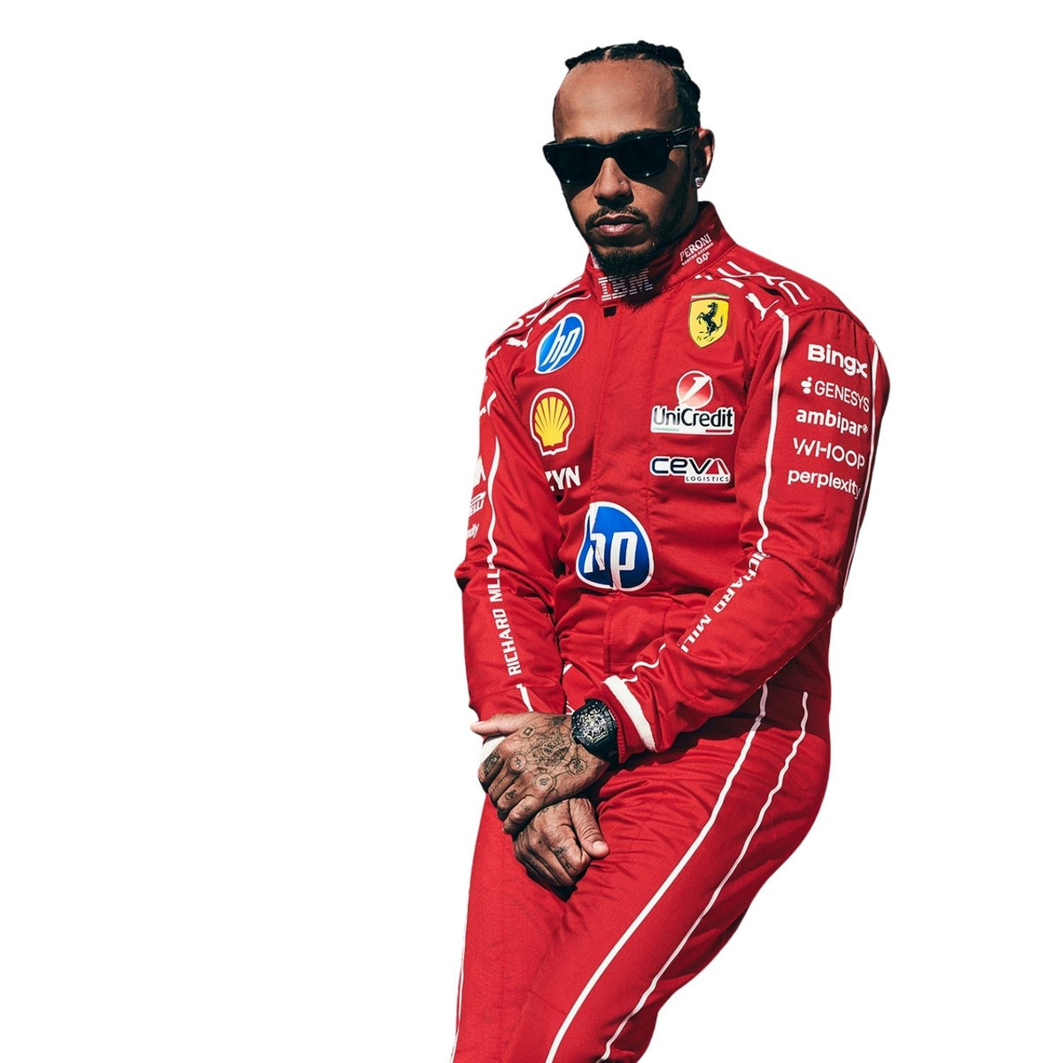 Lewis Hamilton in a red Ferrari racing suit with sponsor logos, wearing black sunglasses and standing against a white background.