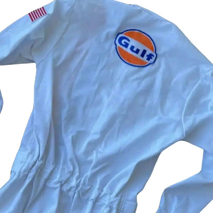 A light blue Michael Delaney 1971 F1 The LeMans Movie Race Costume Porsche Gulf (Steve McQueen) with a large embroidered Gulf logo on the left chest and a small red-and-white striped flag patch on the right sleeve, shown on a plain white background.