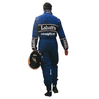 Nigel Mansell 1992 F1 Race Costume Replica Williams behind wearing a blue racing suit with 'Labatt's' and 'Goodyear' logos on the back, holding a black racing helmet against a plain white background.