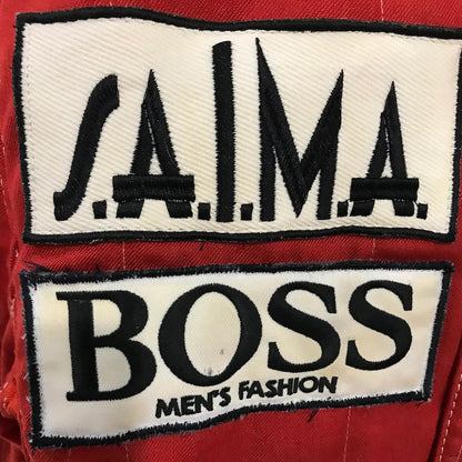 Niki Lauda 1984 F1 Race Costume Replica McLaren World Championship Winning Season Two patches on a red background, one with 'S.A.I.M.A.' and the other with 'BOSS Men's Fashion'.