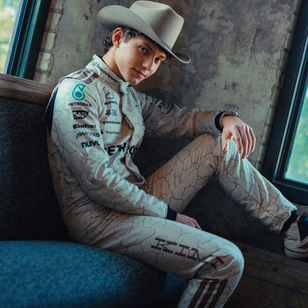 Andrea Kimi Antonelli 2025 F1 Race Suit Replica Mercedes USA Austin GP with sponsor logos sitting on a couch.